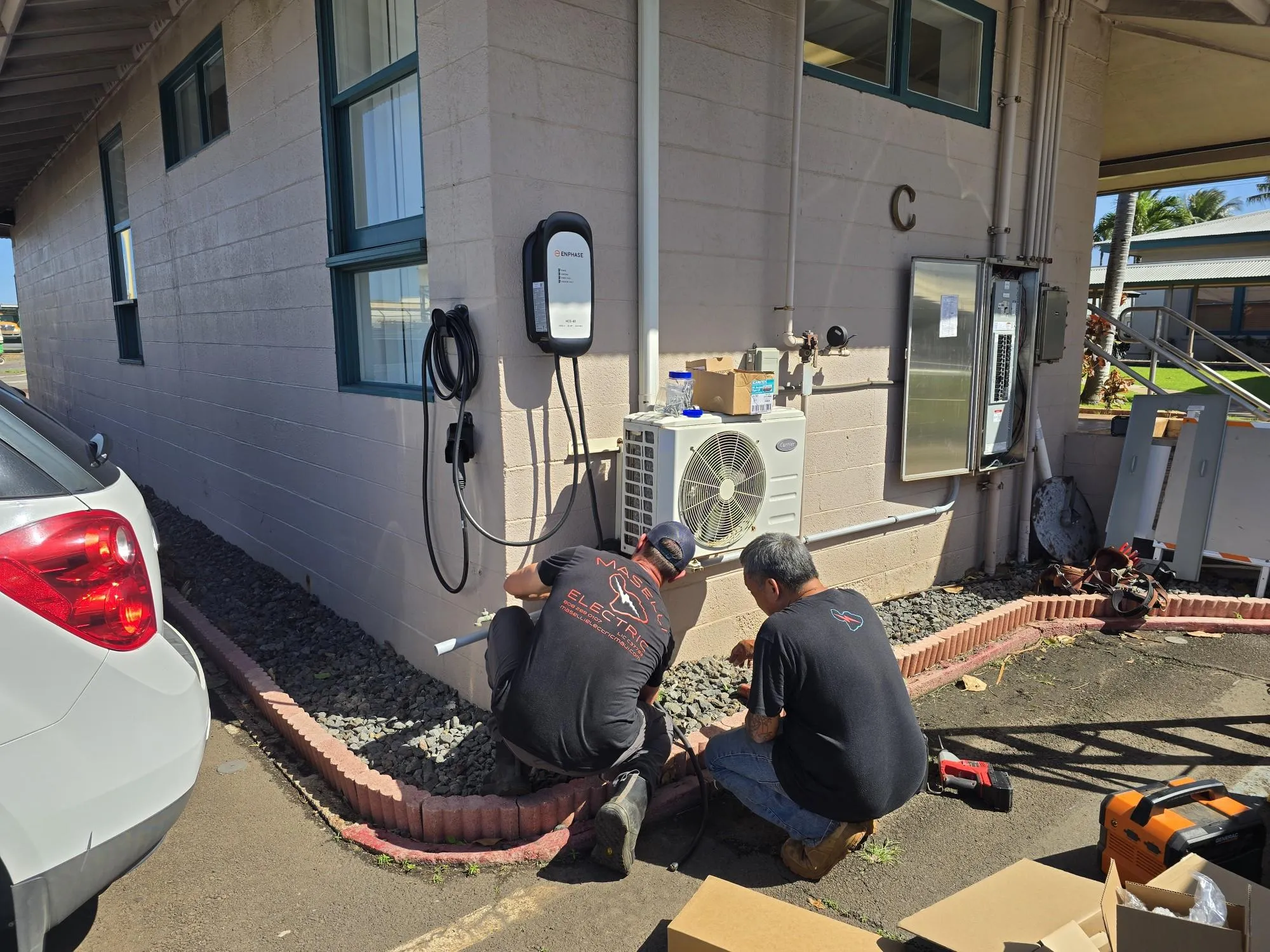 Two Maselli electricians installing EV chargers on a building exterior